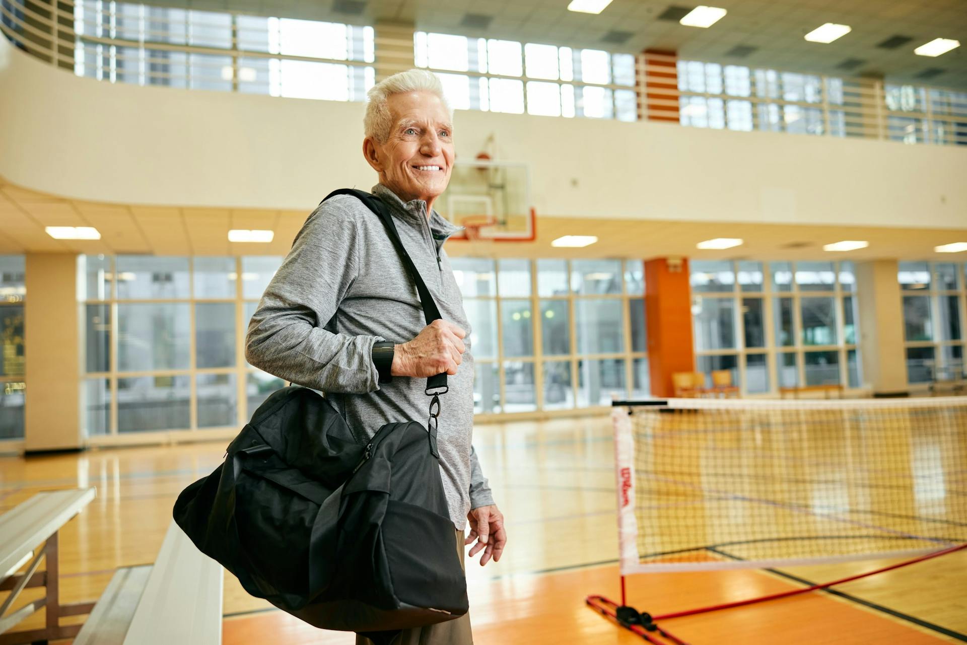 Man with sports bag stands on pickleball court